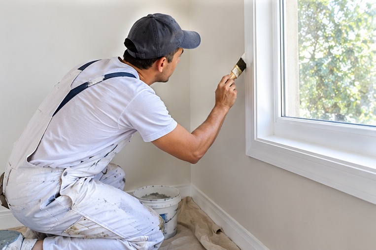 Pintor detallando con brocha el borde de una ventana